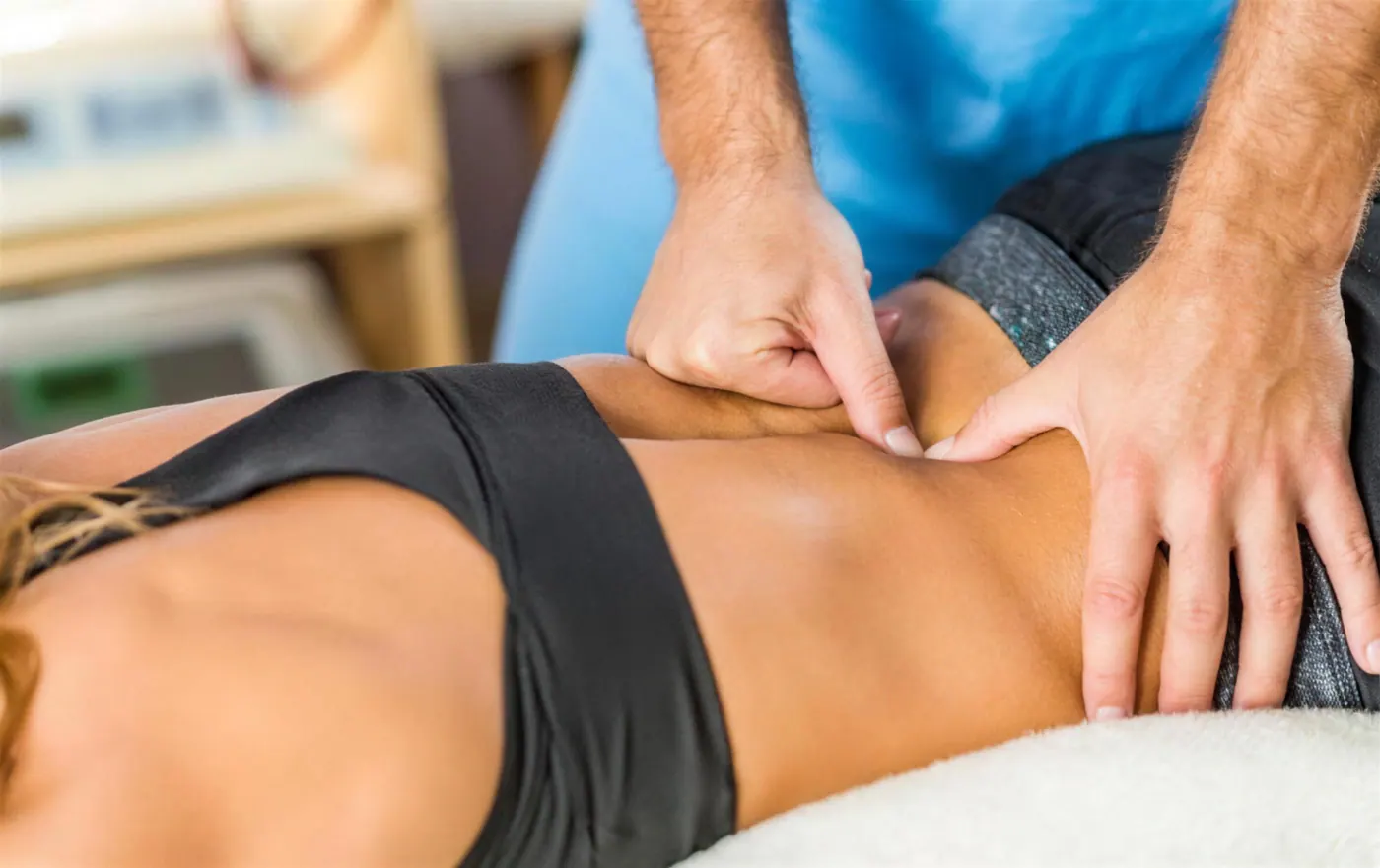 A practitioner's hands working along a client's lower back.
