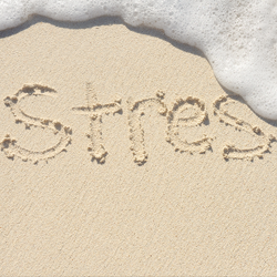 "The word 'Stress' written in the sand partially washed away by a wave"